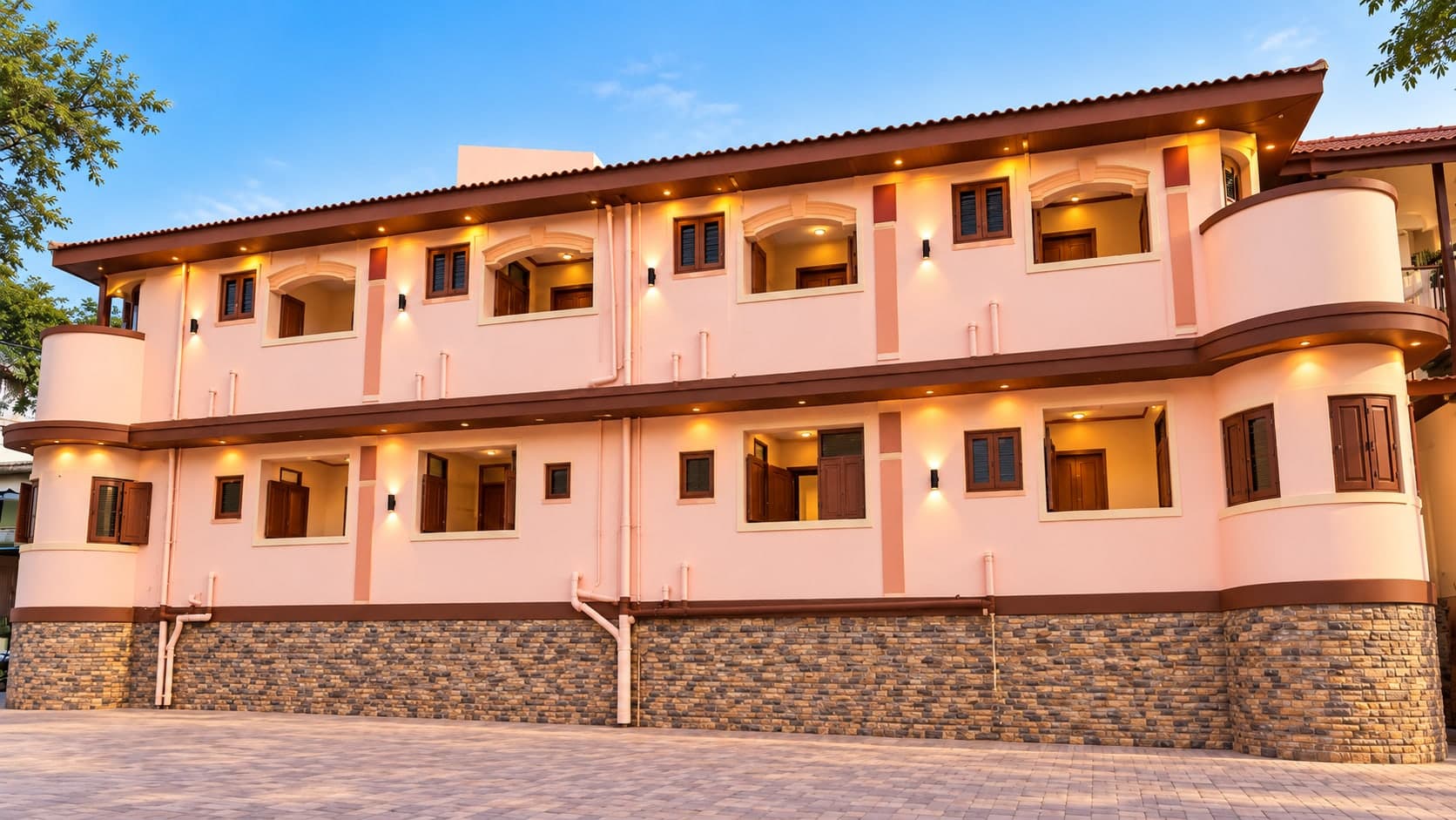 Two-storey peach-coloured Dharamshala building with wooden windows, a tiled sloping roof and warm evening lights