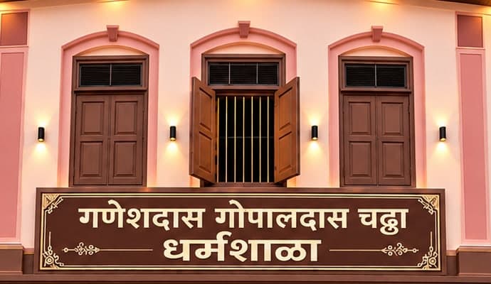 Signboard reading Ganeshdas Gopaldas Chadha Dharamshala below traditional wooden windows